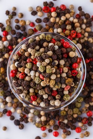 mix of peppercorns on white acrylic background.