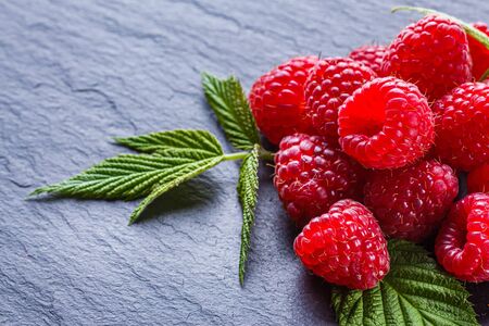 juicy fresh natural raspberries on a dark stone background.