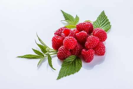 Juicy fresh natural raspberries on white acrylic background.