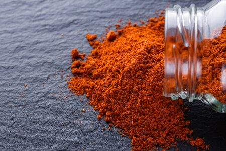 aromatic spicy chilli powder on a dark stone background.