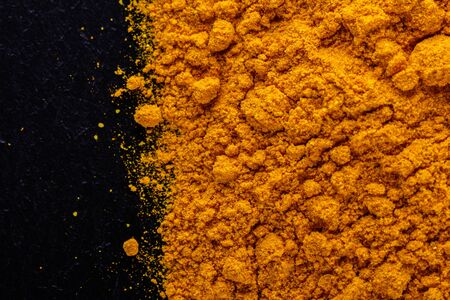 natural turmeric powder on a dark stone background.の写真素材