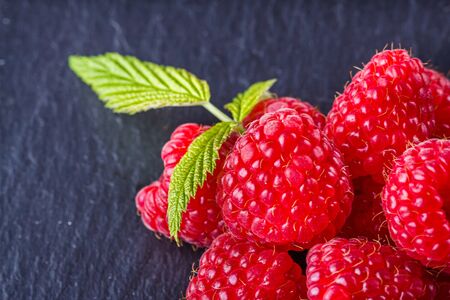 juicy fresh natural raspberries on a dark stone background.の写真素材