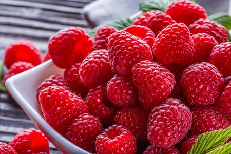 juicy fresh natural raspberries on a dark wooden rustic background.