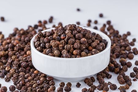 fragrant black pepper on white acrylic background.の写真素材
