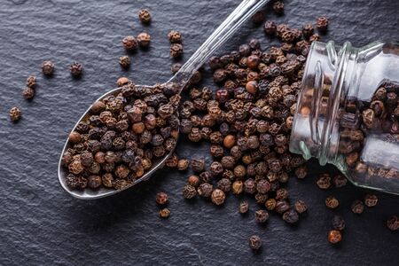 aromatic black pepper on a dark stone background.の写真素材