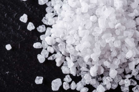 coarse sea salt on a dark stone background.