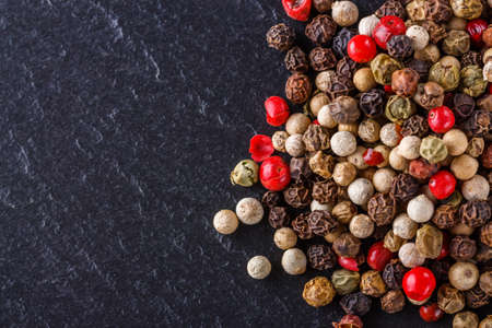 mix of peppercorns on a dark stone background.の写真素材