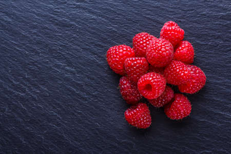 juicy fresh natural raspberries on a dark stone background.