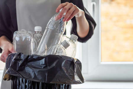 young female housewife throws away empty plastic bottles.
