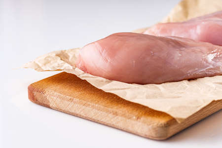 raw chicken fillet on a white acrylic background.