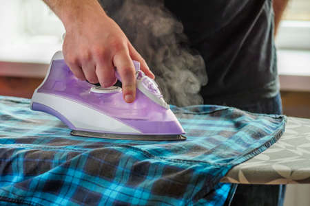 young woman housewife irons her husband's shirt.の写真素材