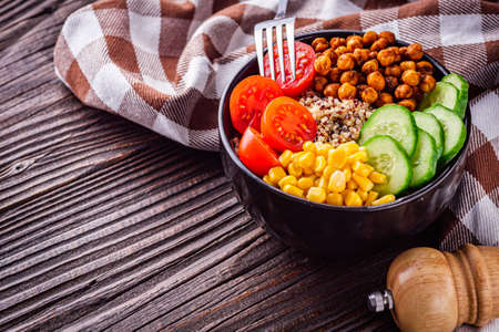 bowl of healthy quinoa with vegetables on a dark rustic background.の写真素材