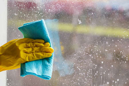 young woman housewife washes a dirty window.の写真素材