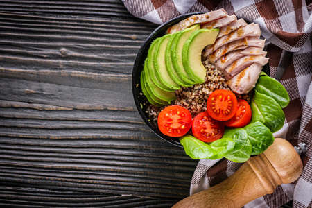 bowl of healthy quinoa with grilled chicken and vegetables on a dark rustic background.の写真素材