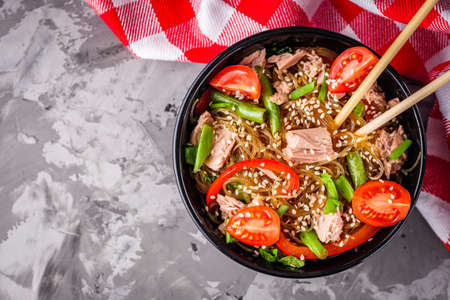 delicious glass noodles with tuna and vegetables on a dark stone background.の写真素材