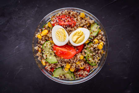 bowl of healthy quinoa with vegetables on a dark rustic background.の写真素材