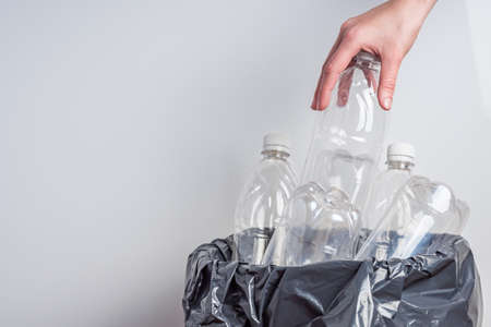 young female housewife throws away empty plastic bottles.の写真素材