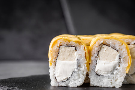 appetizing cheese sushi roll with philadelphia and tofu cheese on a black stone plate.の写真素材