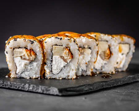 appetizing sushi roll california with eel tofu sesame and unagi cheese on a black stone plate.の写真素材