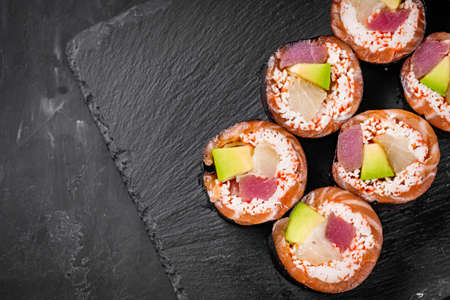 appetizing sushi roll with tuna salmon escolar crab and avocado on a black stone plate.の写真素材