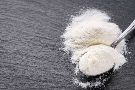granulated milk powder on a dark stone background.の写真素材