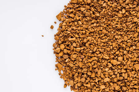 instant coffee granules on a white acrylic background.