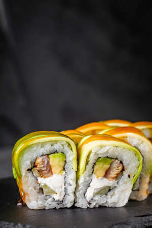 appetizing green dragon roll with philadelphia cucumber eel and avocado cheese on a black stone...
