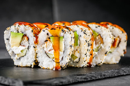 appetizing sushi roll california with eel avocado cucumber and sesame seeds on a black stone plate.の写真素材