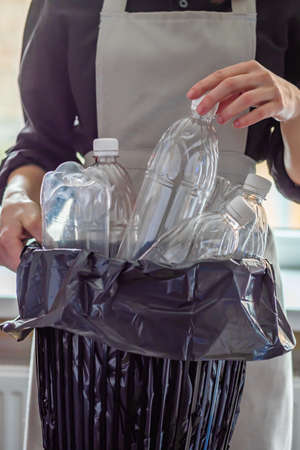 young female housewife throws away empty plastic bottles.