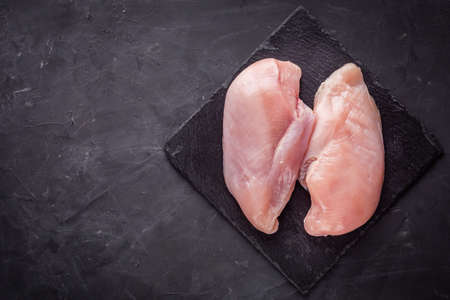 raw chicken fillet on a dark stone background.の写真素材