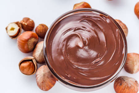 chocolate butter and hazelnuts on a white acrylic background.