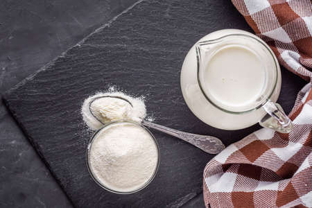granulated milk powder on a dark stone background.
