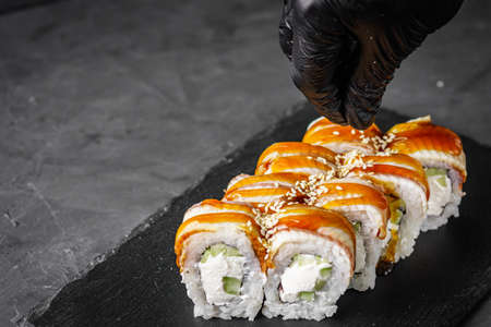 appetizing Philadelphia roll with eel and cucumber on a black stone plate.
