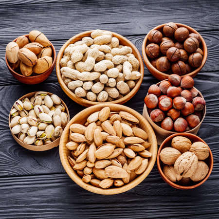 set of different nuts on a black rustic wooden background.