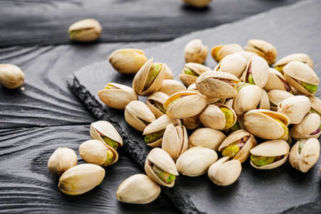 fresh salted pistachios on a black stone wooden rustic background.