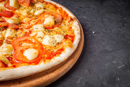 hot delicious traditional italian pizza on a dark stone background.