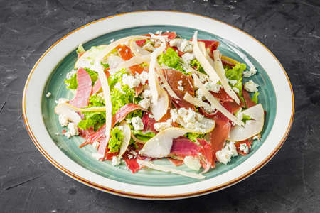 prosciutto salad with parmesan pear and blue cheese on a black background.の写真素材