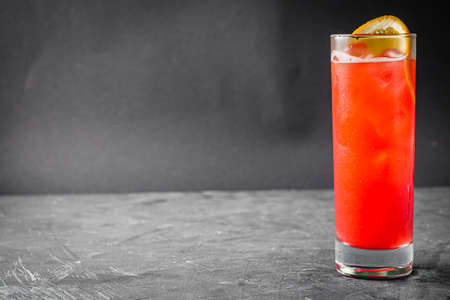 bright colored alcoholic cocktail on a black stone background.