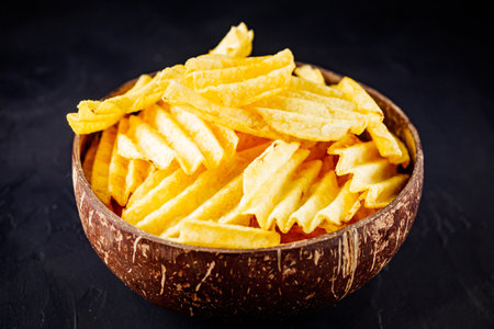 golden crispy potato chips on a dark background.