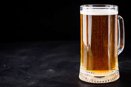 mug of beer and a set of dry fish snacks on a dark background.