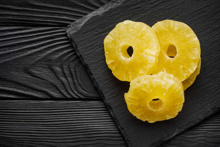 delicious dried pineapple on a black wooden rustic background.の写真素材