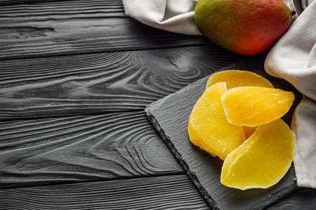 delicious dried mango on a black wooden rustic background.