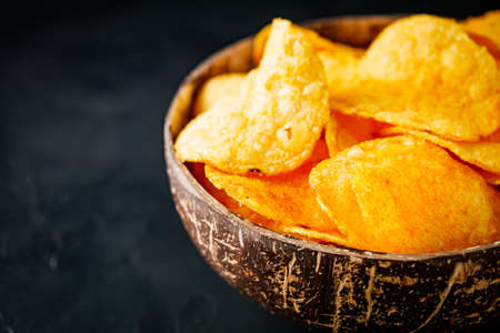 golden crispy potato chips on a dark background.の写真素材