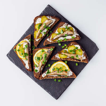 canapes with sprats on a black stone tray.