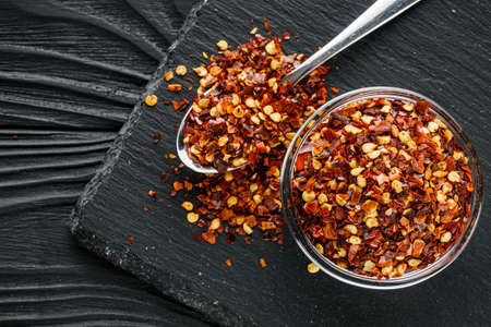 spicy chili flakes on a dark stone background.
