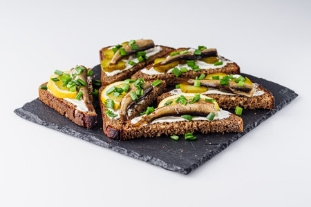 canapes with sprats on a black stone tray.