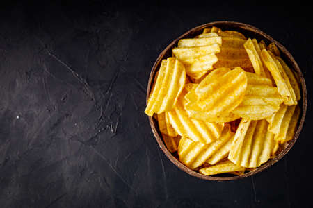 golden crispy potato chips on a dark background.の写真素材