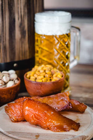 mug of beer and a set of dry fish snacks on a dark rustic wooden background.の写真素材