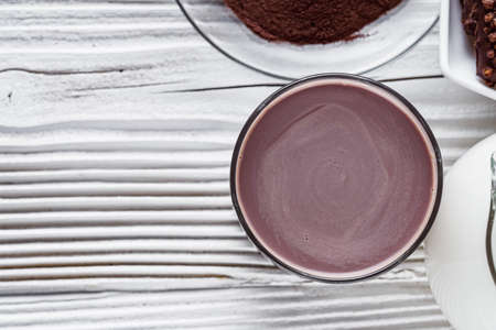 chocolate cocoa milk powder on a white wooden rustic background.
