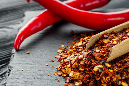 spicy chili flakes on a dark stone background.の写真素材